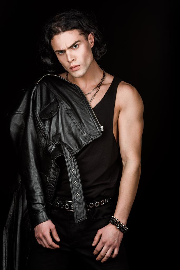 handsome and serious man in leather jacket looking at camera isolated on black  - Photo, Image