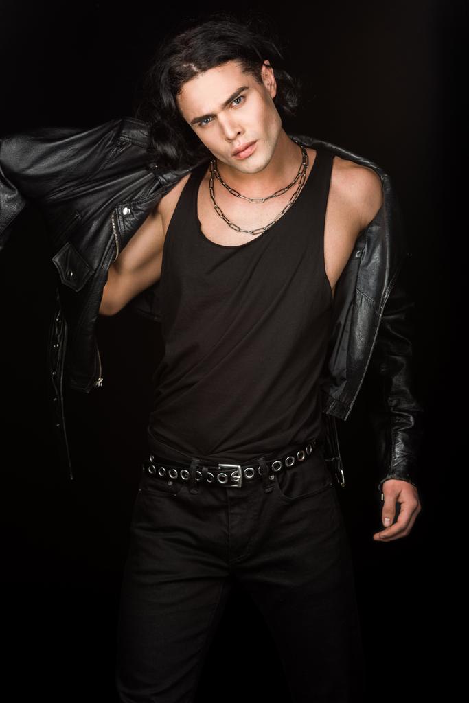 handsome man wearing leather jacket and looking at camera isolated on black  - Photo, Image