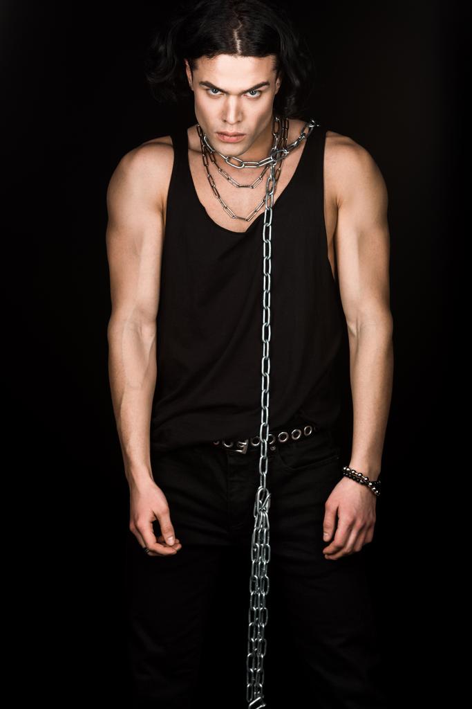 hombre guapo en camiseta de pie con cadenas en el cuello aislado en negro
  - Foto, imagen