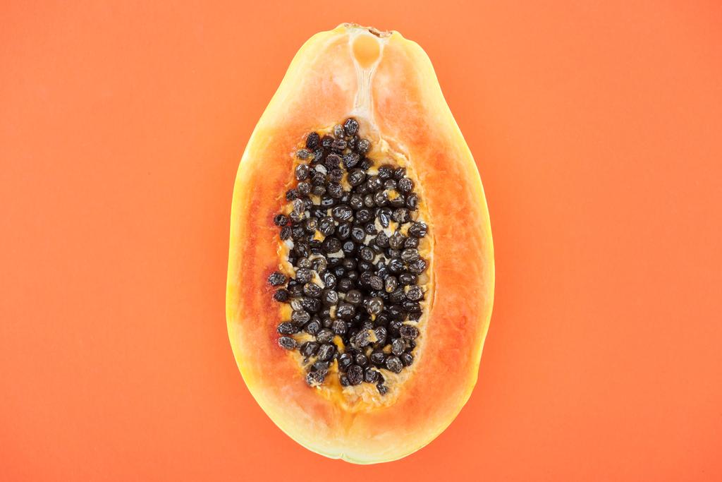 vista superior de la mitad madura de papaya tropical con semillas negras aisladas en naranja
 - Foto, imagen