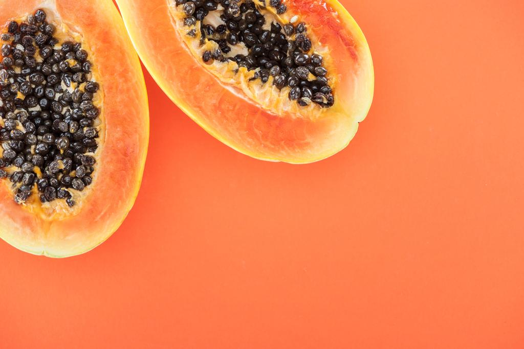 オレンジ色に分離された黒い種子を持つ熟した熱帯パパイヤの半分のトップビュー - 写真・画像