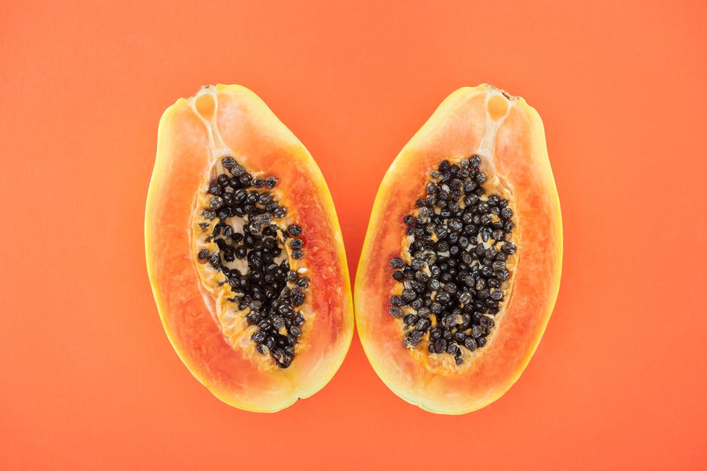 widok na dojrzałe jasne połówki papai z czarnymi nasionami na pomarańczowo - Zdjęcie, obraz
