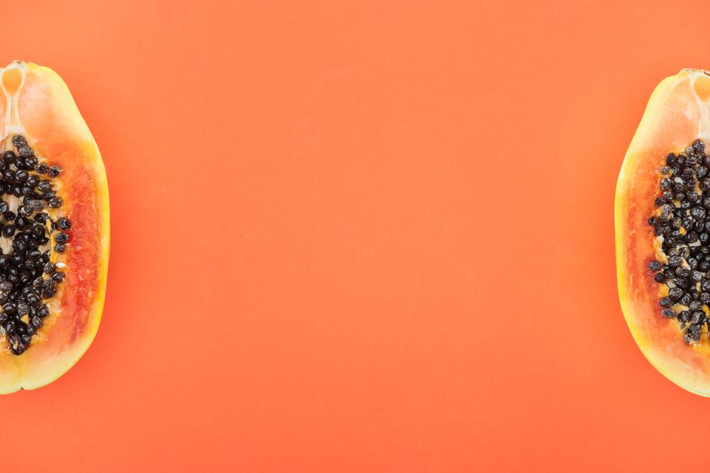 верхний вид спелых половинки папайи с черными семенами изолированы на апельсин
 - Фото, изображение