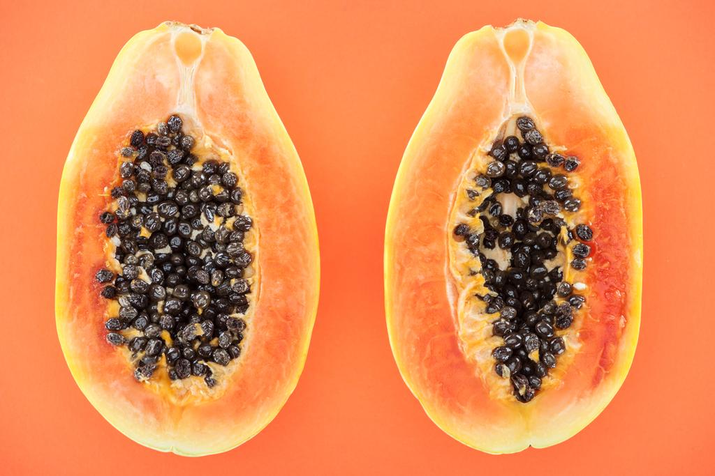 Widok z góry na dojrzałe egzotyczne połówki papai z czarnymi nasionami na pomarańczowo - Zdjęcie, obraz