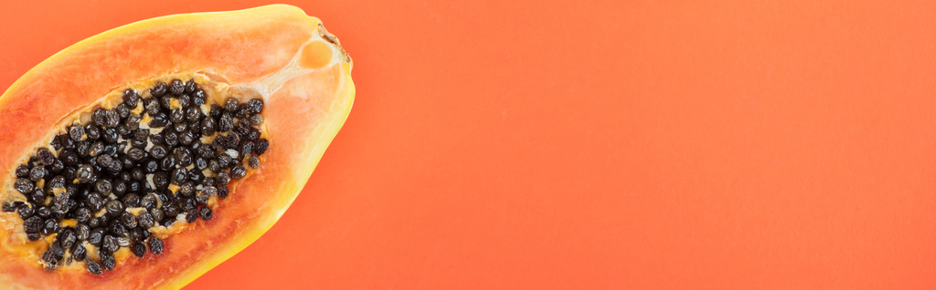 panoramiczny strzał dojrzałej egzotycznej papai z czarnym nasion wyizolowanych na pomarańczowo - Zdjęcie, obraz