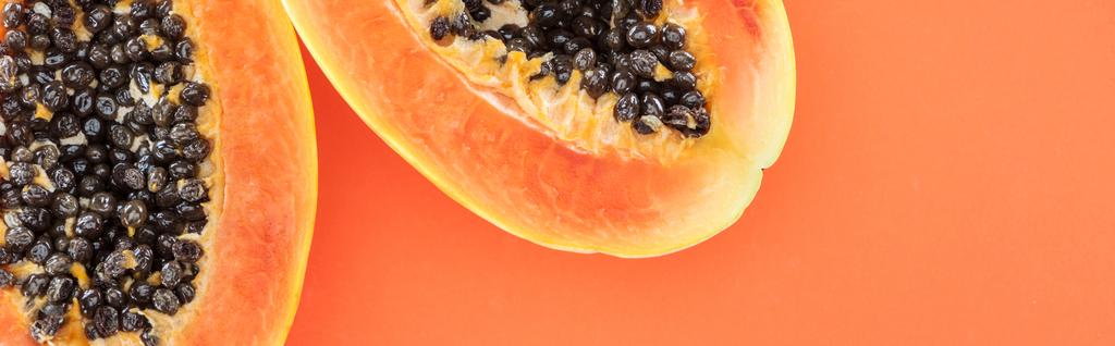 オレンジ色に隔離された黒い種子を持つ熟したパパイヤの半分のパノラマショット - 写真・画像