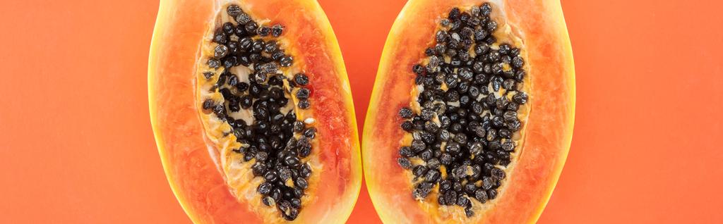 panoramische Aufnahme reifer exotischer Papayahälften mit schwarzen Samen auf Orange - Foto, Bild