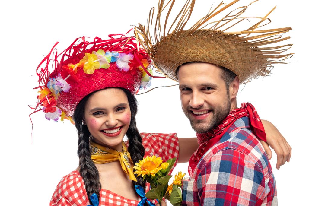šťastný muž a mladá žena v sváteční šatech s slunečnic, které se dívají na kameru izolovanou na bílém - Fotografie, Obrázek