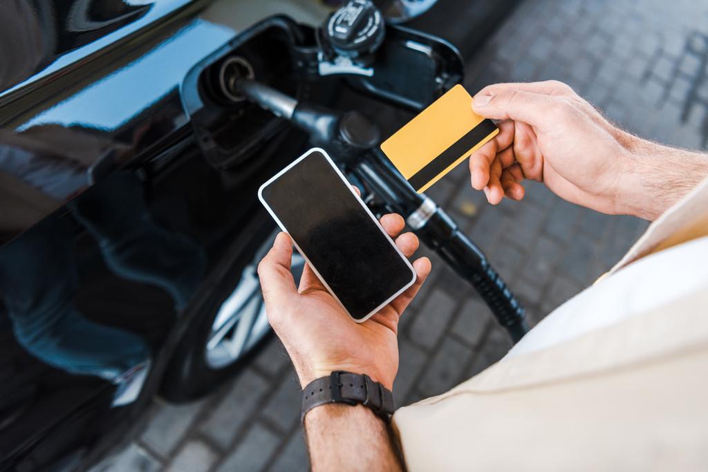 vista cortada de homem segurando cartão de crédito perto de smartphone com tela em branco
  - Foto, Imagem