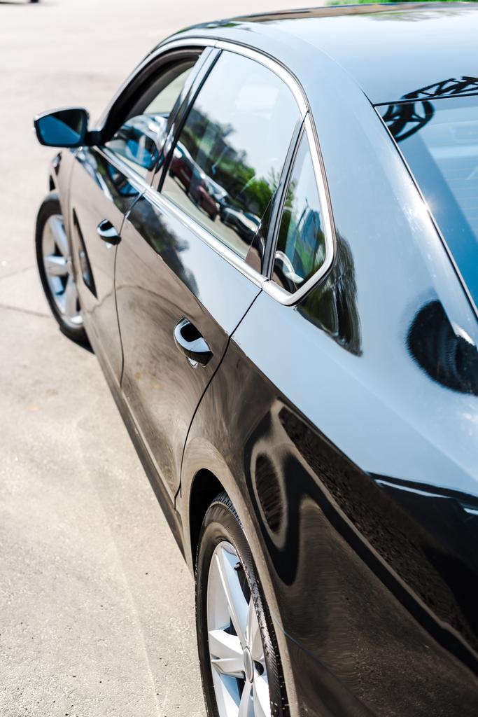 επιλεκτική εστίαση του λαμπερό μαύρο και μοντέρνο αυτοκίνητο στο χώρο στάθμευσης - Φωτογραφία, εικόνα