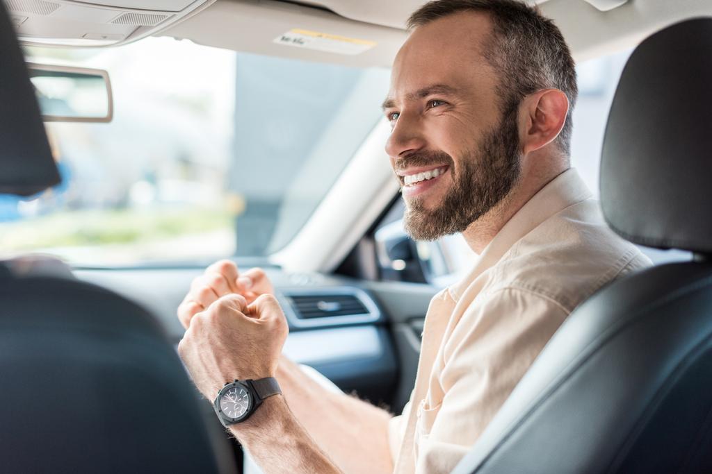 cheerful man gesturing while smiling and sitting in car  - Photo, Image