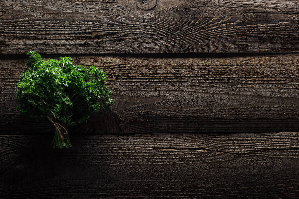 Draufsicht auf grüne Petersilie auf verwittertem Holztisch mit Kopierraum - Foto, Bild