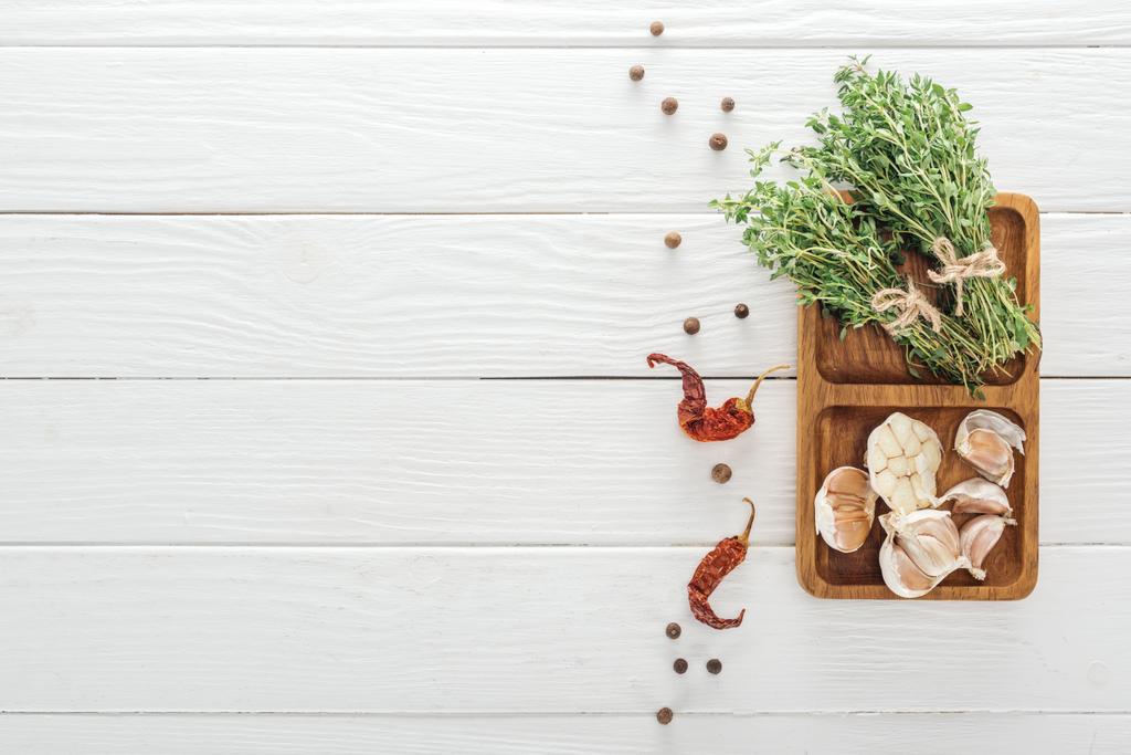 vue du dessus de piments secs, poivre noir près de la planche avec gousses d'ail et thym sur table en bois blanc
 - Photo, image