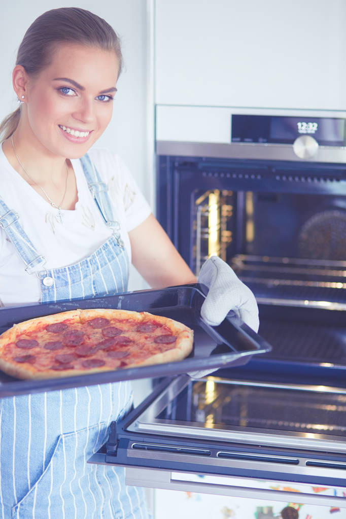 Glückliche junge Frau kocht zu Hause Pizza - Foto, Bild