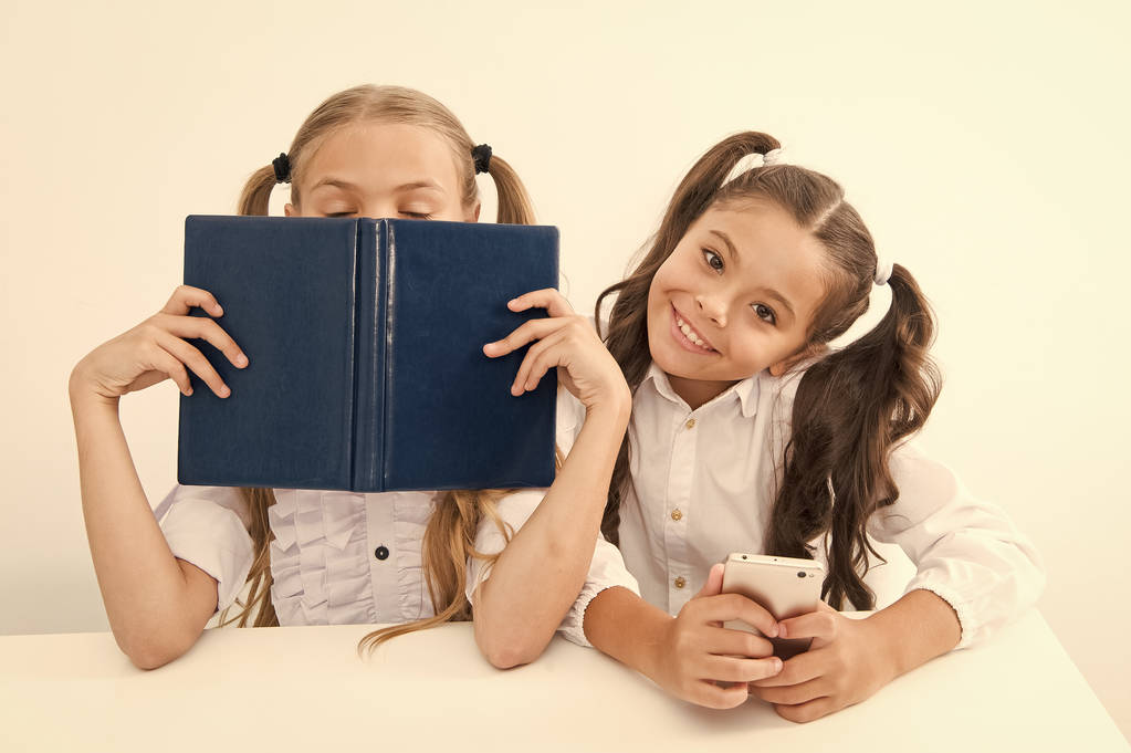 近代に対抗する古い学校。彼女の友人はアナログデータストレージとして古い本を楽しんでいる間女子高生は、携帯電話の近代的なスマートフォンを保持します。経験に対する技術。新世代の教育需要 - 写真・画像