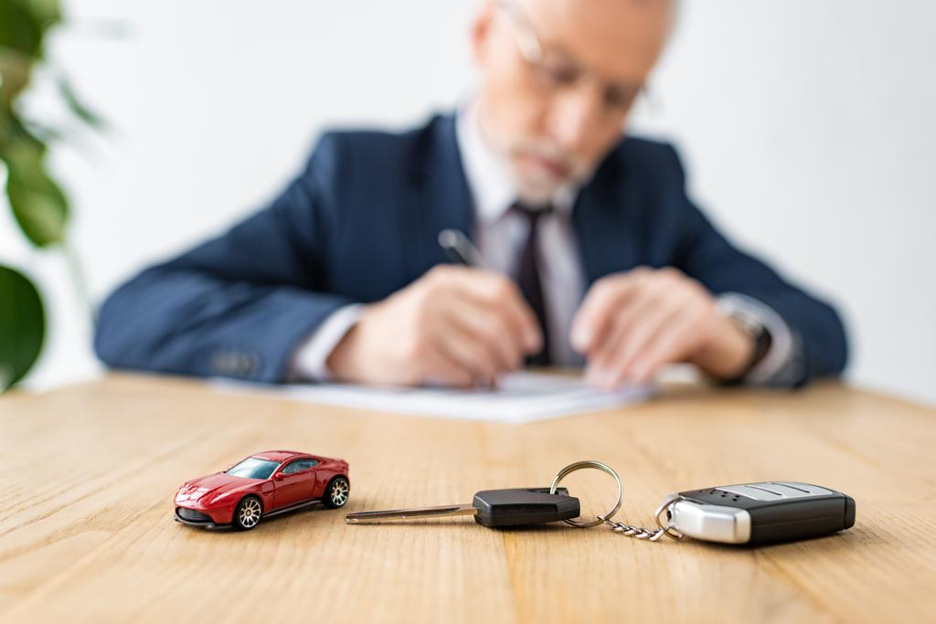 selective focus of toy car and car key near car dealer in office  - Photo, Image