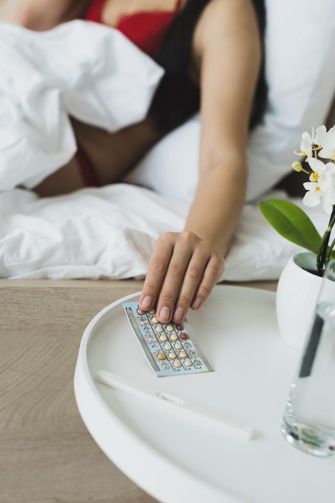 partial view of woman taking birth control pills from bedside table  - Photo, Image