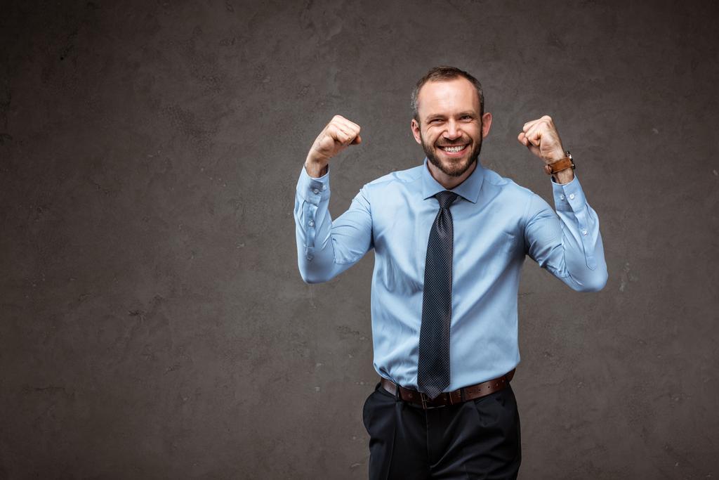 homem de negócios feliz em terno gestos enquanto comemorando em cinza
  - Foto, Imagem