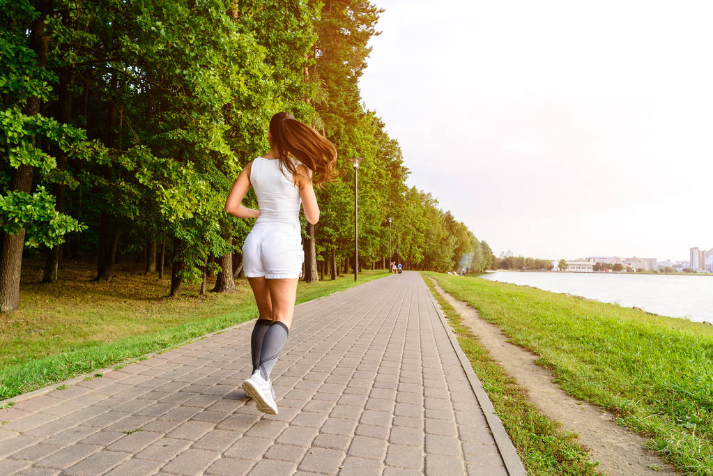 Kaunis nainen juoksee sillalla jokapäiväisessä harjoittelussa. Fitness nainen lenkkeily ulkona puistossa
 - Valokuva, kuva