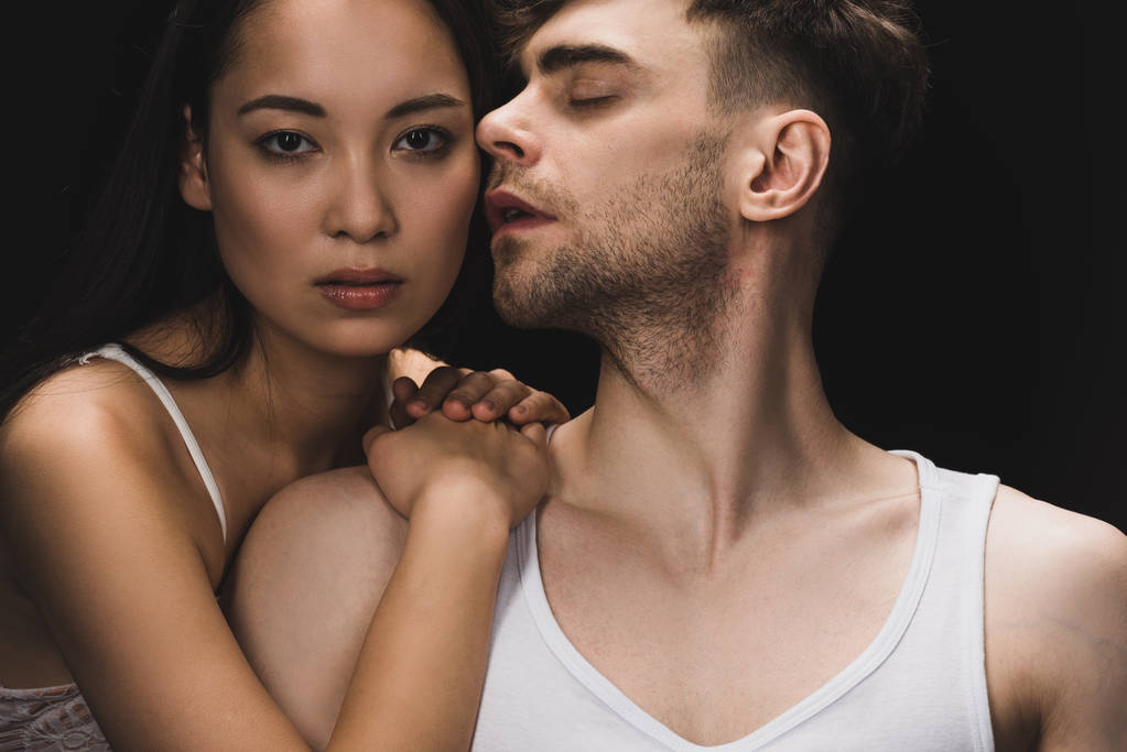 atractivo asiático mujer acostado en hombro de guapo novio y mirando la cámara aislado en negro
 - Foto, Imagen