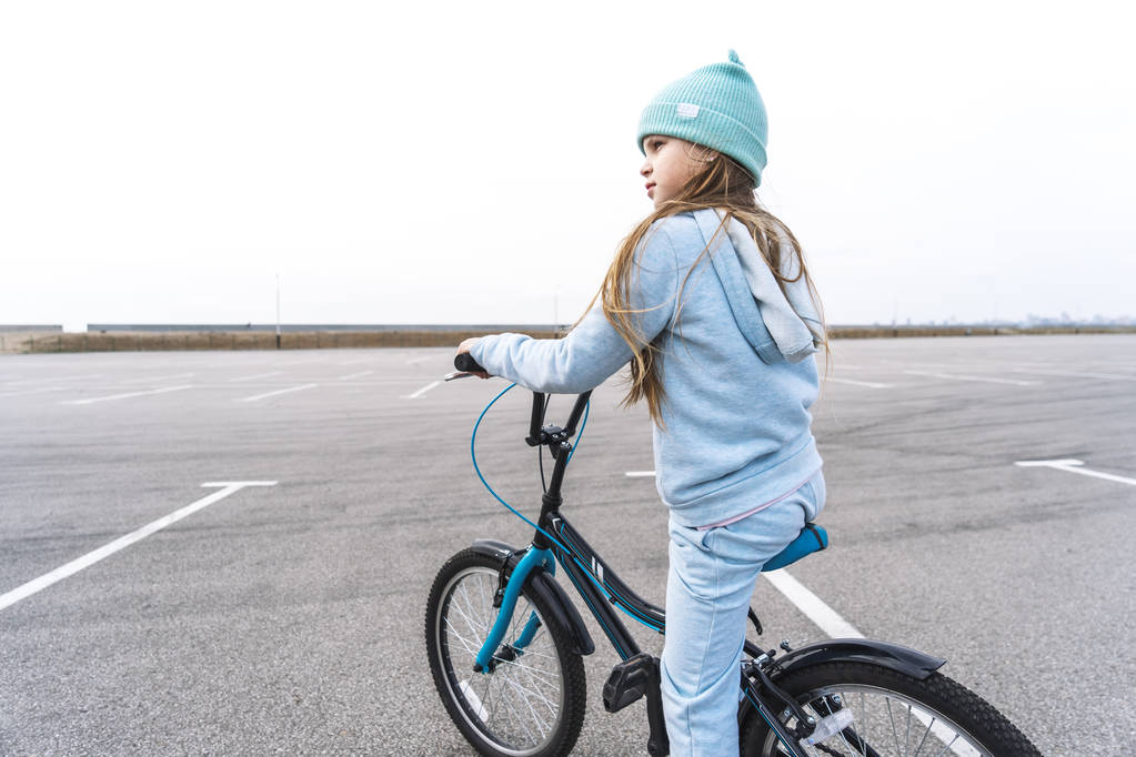 Девушка в шляпе и голубом свитере на велосипеде остановилась и огляделась вокруг
. - Фото, изображение