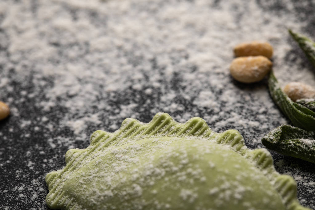 黒いテーブルの上に緑のラビオリと散らばった小麦粉の選択的な焦点 - 写真・画像