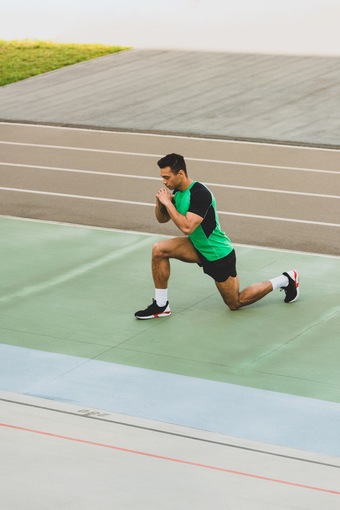mixed race Sportsman in sportkleding stretching in het stadion - Foto, afbeelding