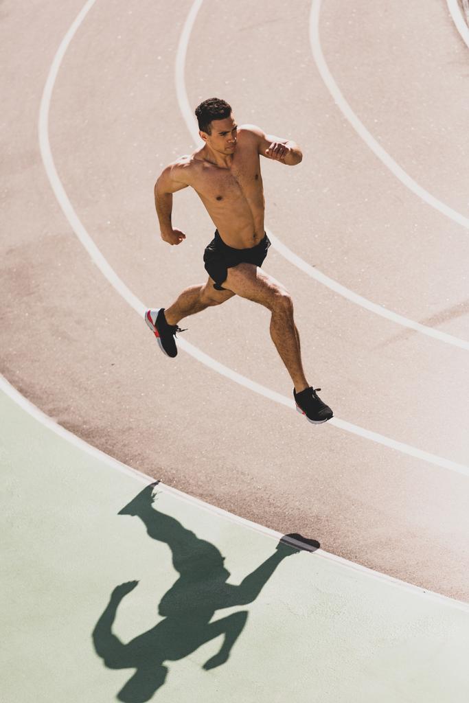 yleiskuva stadionilla juoksevasta sekarotuisesta urheilijasta
 - Valokuva, kuva
