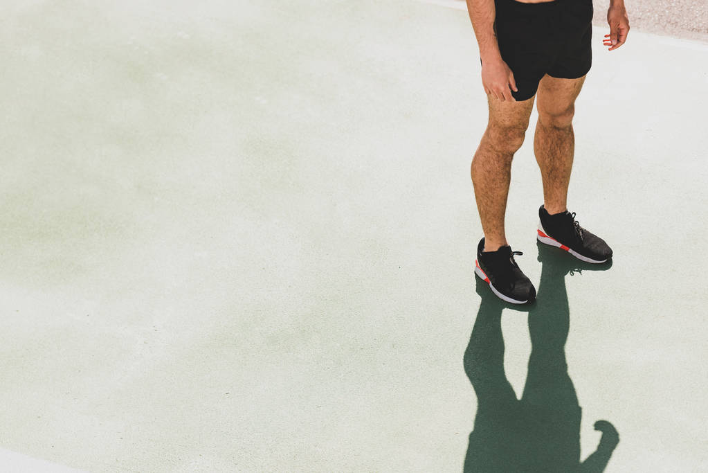 обрізаний вид на спортсмена в чорних кросівках, стоячи на стадіоні
 - Фото, зображення