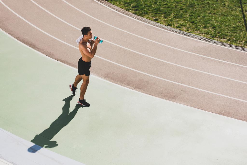 εναέρια θέα του μεικτού αθλητή που κρατά πετσέτα και πόσιμο νερό στο στάδιο - Φωτογραφία, εικόνα
