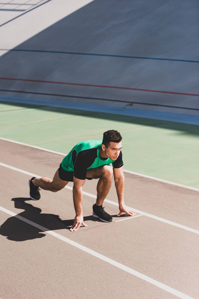 mixed race sportsman preparing to run at stadium - Photo, Image