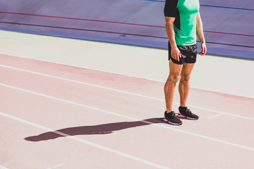 обрезанный вид спортсмена в спортивной одежде, стоящего на стадионе
 - Фото, изображение