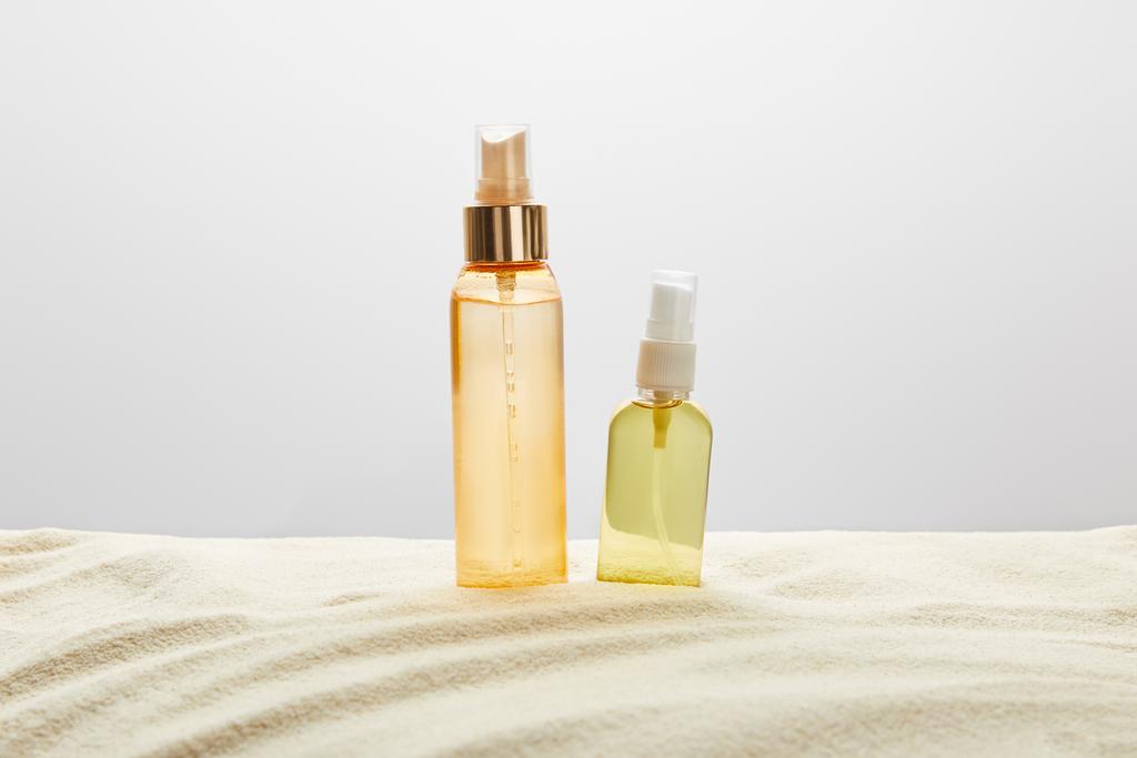 sunscreen products in transparent bottles in sand on grey background - Photo, Image