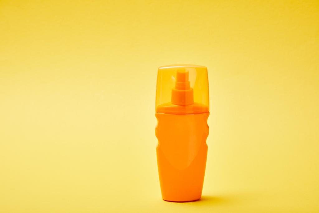sluneční clona v oranžovém láhvi na barevném žlutém pozadí - Fotografie, Obrázek
