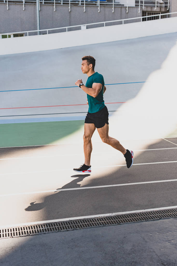 koşu pistinde karışık yarış sporcusu jogging yan görünümü  - Fotoğraf, Görsel