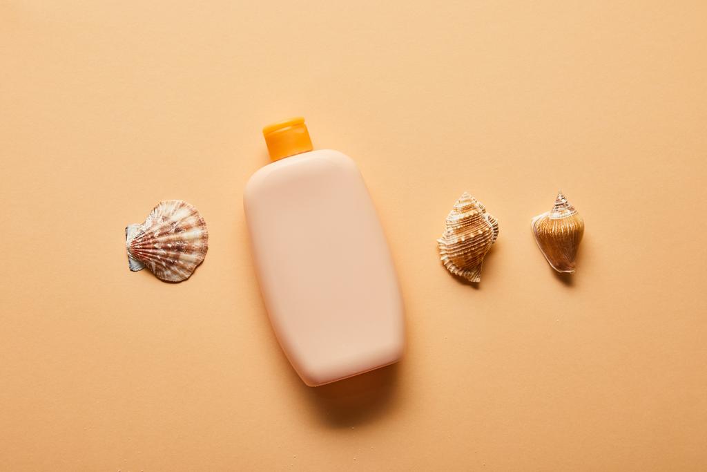 tumbado plano con crema solar en botella y conchas sobre fondo beige
 - Foto, Imagen