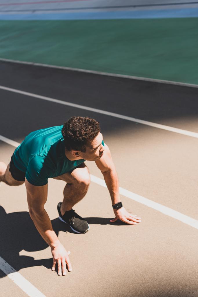 mixed race Sportsman op startpositie op Running track, op weg naar het stadion - Foto, afbeelding