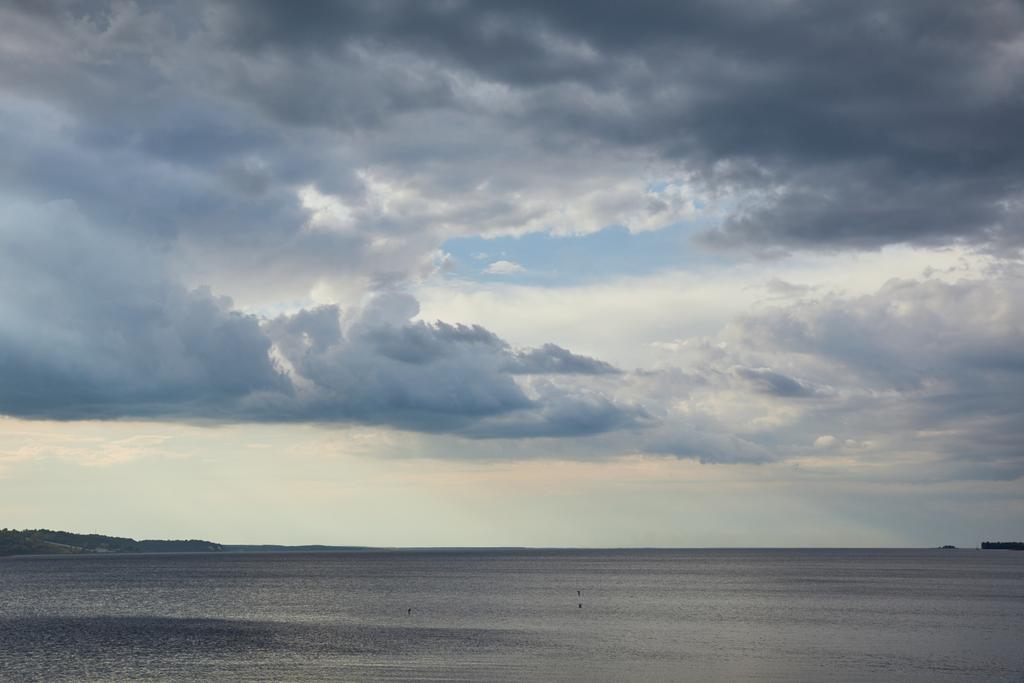 Погода пасмурная с облаками на голубом небе над береговой линией реки
 - Фото, изображение