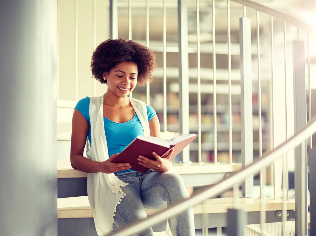 Afrikaanse student meisje leesboek bij bibliotheek - Foto, afbeelding