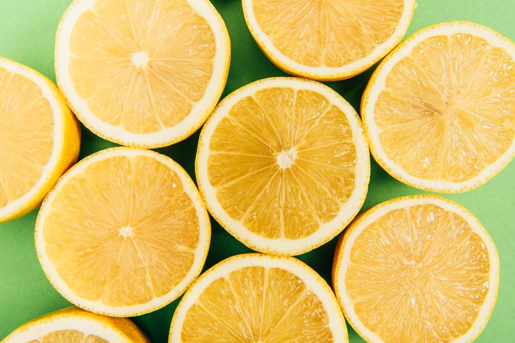 Закрыть вид ярко-желтых срезанных лимонов на цветном зеленом фоне
 - Фото, изображение