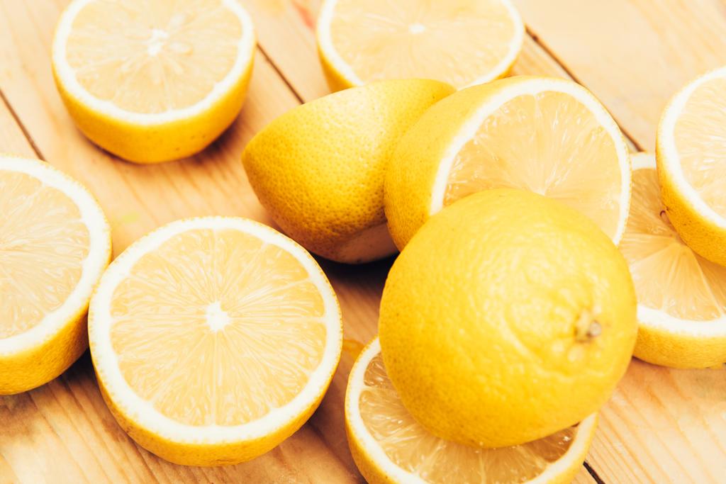 Close up view of juicy, fresh and yellow cut lemons on wooden surface background - Photo, Image