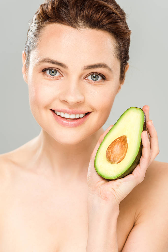 щаслива гола жінка тримає половину органічного і стиглого авокадо ізольовано на сірому
  - Фото, зображення