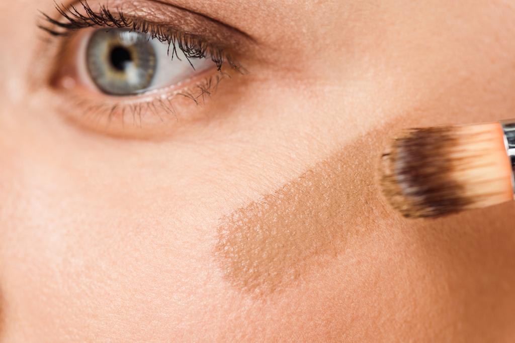 女性の頬に茶色の赤面を持つ化粧品ブラシのトリミングビュー   - 写真・画像