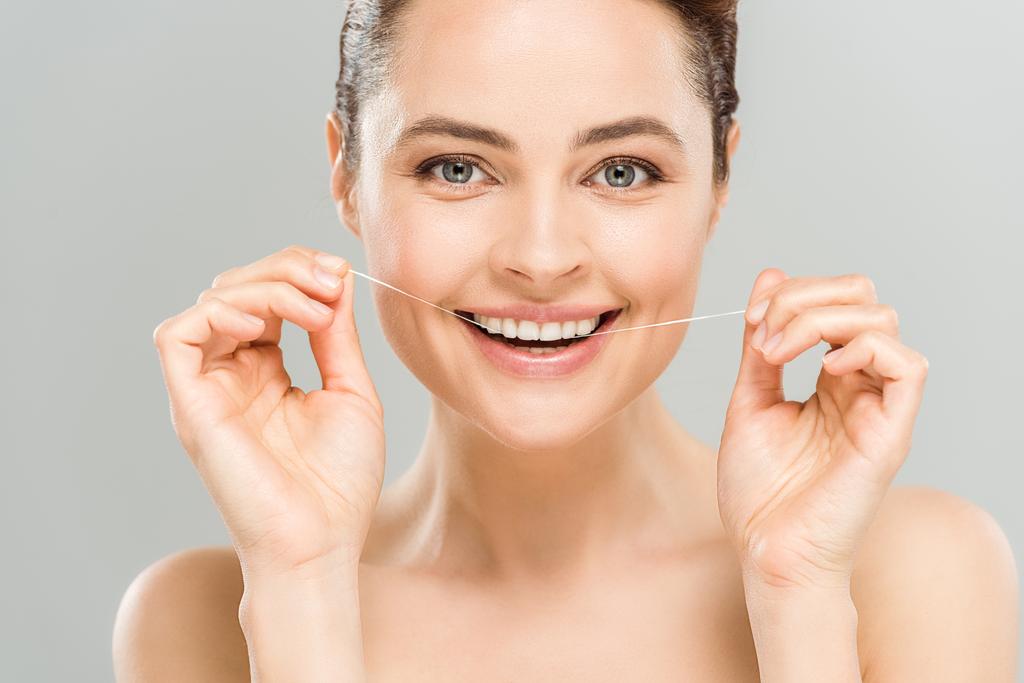 ευτυχισμένη γυμνή γυναίκα οδοντικό νήμα δόντια με οδοντικό νήμα απομονωθεί σε γκρι  - Φωτογραφία, εικόνα