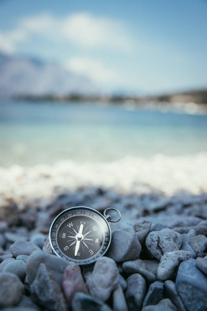 Kompassi rannalla, pienet kivet, tekstitila
 - Valokuva, kuva
