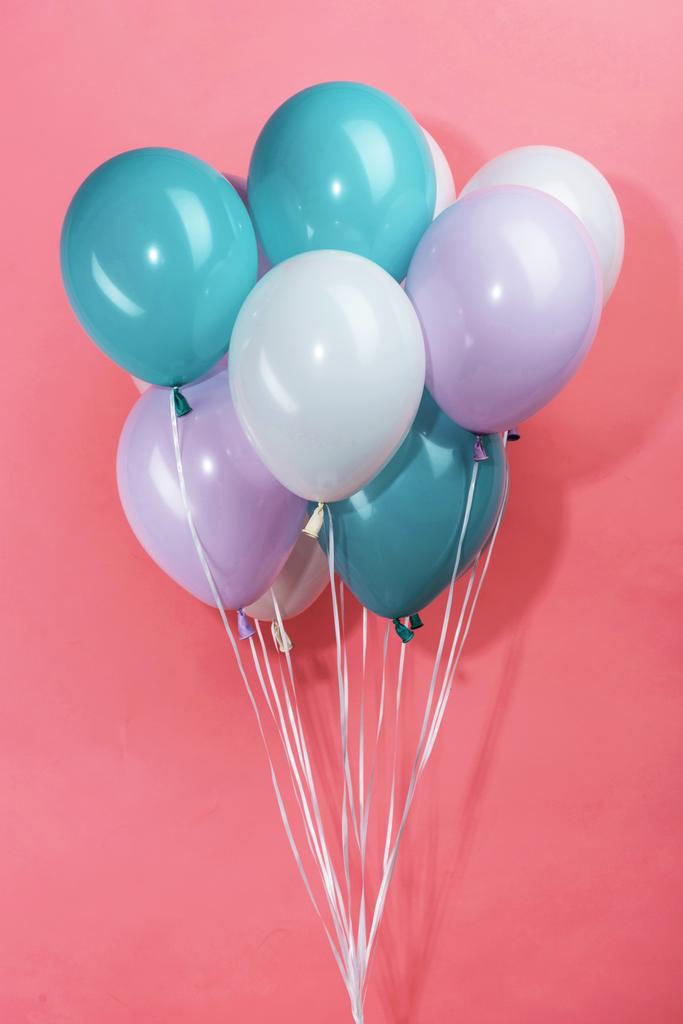 πολύχρωμα λευκά, μπλε και μωβ διακοσμητικά γιορτινά μπαλόνια σε ροζ φόντο - Φωτογραφία, εικόνα