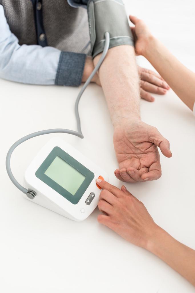 Cropped view of woman pressing button on blood pressure meter with copy space on display - Photo, Image