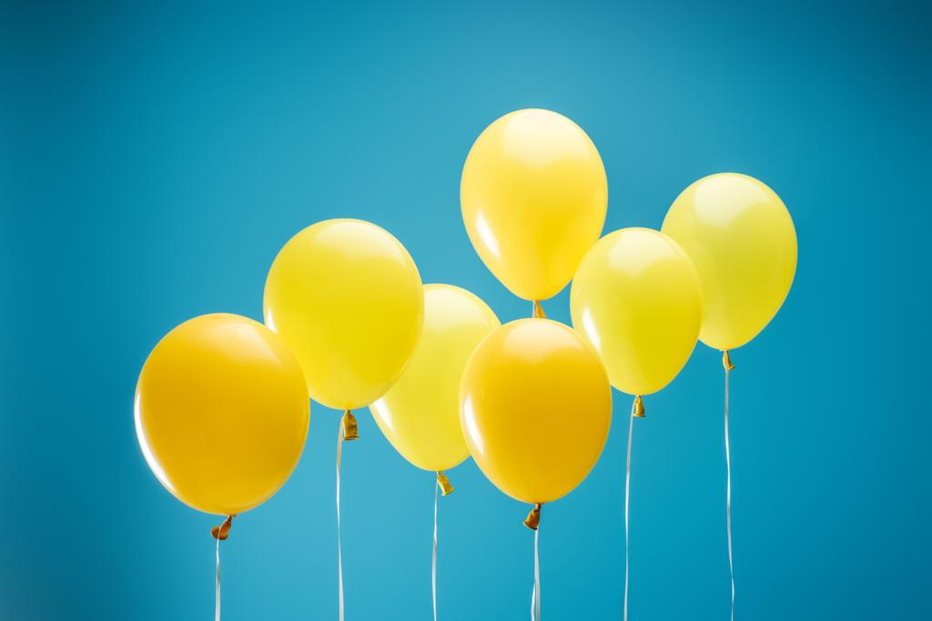bright colorful yellow balloons on blue background - Photo, Image
