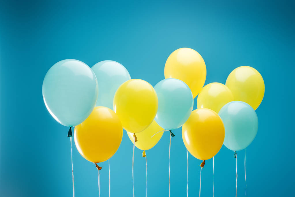 πολύχρωμα κίτρινα και μπλε μπαλόνια σε μπλε φόντο - Φωτογραφία, εικόνα