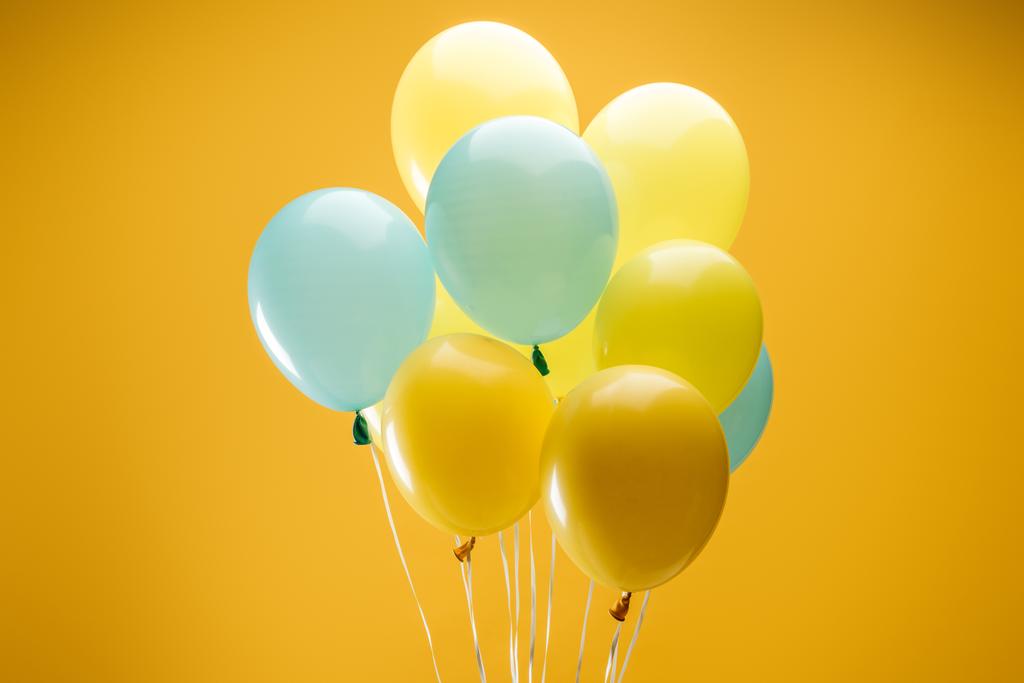εορταστικά μπλε και κίτρινα μπαλόνια σε κίτρινο φόντο - Φωτογραφία, εικόνα